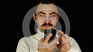 Man typing text message on smartphone over black background.