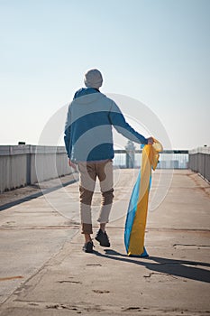 Man with a Ukrainian flag goes to join a demonstration in support of Ukraine. A demonstration against war and atrocities in the