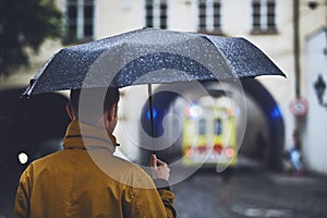 Man with umbrella looking at leaving ambulance car