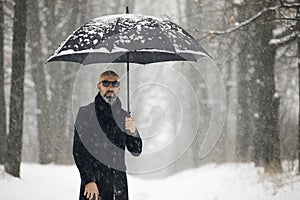 Man with umbrella in the park during a snowfall