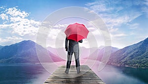 Man with umbrella standing on te pier