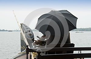 Man with umbrella steers a Houseboat