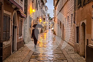 A man with an umbrella on the street in Porec town.