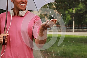 Man with umbrella walking under rain in park, closeup