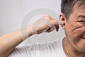 Man un-hygienically cleaning ear using finger with ticklish expression photo