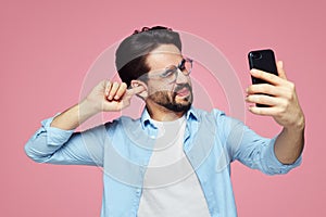 Man un-hygienically cleaning ear using finger with ticklish expression while using a smartphone photo