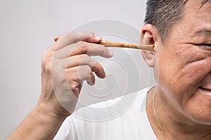 Man un-hygienically cleaning ear using wooden stick photo