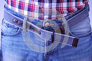 Man unbuttons his jeans belt by hands. photo