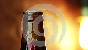 Man uncork a bottle of beer with foam with ice frozen drops, on gold brown background, fun and nutrition