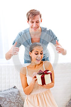 Man uncover eyes of girlfriend with present