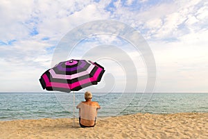 Man under beach umbrella for shadow