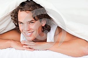 Man under a duvet with a knowing smile