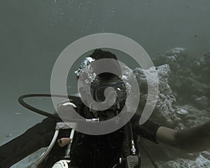 A man under the ocean is seen weared the oxygen mask and the diving accessories