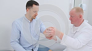 A man undergoes an examination of the elbow joint by a doctor