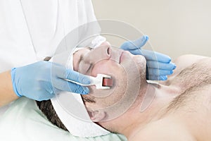 Man undergoes the procedure of medical micro needle therapy with a modern medical instrument derma roller.