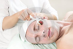 Man undergoes the procedure of medical micro needle therapy with a modern medical instrument derma roller.