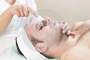 Man undergoes the procedure of medical micro needle therapy with a modern medical instrument derma roller. photo