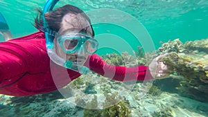 Man in an underwater mask is snorkeling in clear water. Underwater scene diver near rock of corals in Indian ocean.