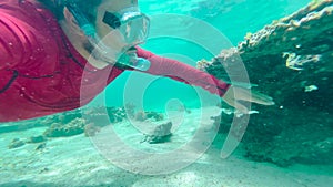 Man in an underwater mask is snorkeling in clear water. Underwater scene diver near rock of corals in Indian ocean.