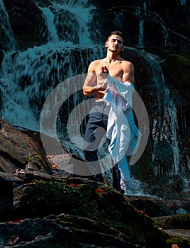 Man undressing at waterfall ready to swim. business trip. summer vacation traveling. Agile business. Money waterfall and