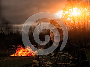 A man in uniform armed with a fire. Smile of the prankster. In the background, the building burns photo