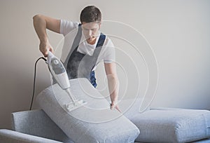 Man in uniform cleaning sofa.