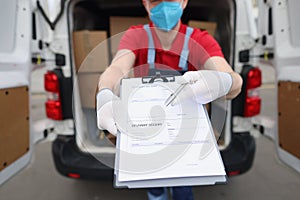 Man in uniform and face mask give delivery receipt paper to receiver to sign