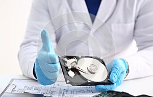 Man in uniform hold disassembled hard drive from computer, hdd and reader, show thumbs up