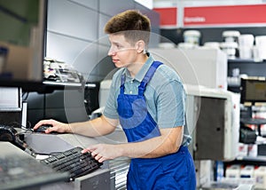 Man in uniform operating computerised machne to mix paint photo