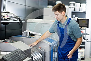 Man in uniform operating computerised machne to mix paint photo