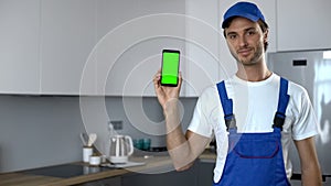 Man in uniform showing phone with green screen, booking of house repair service