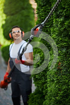 Man in uniform trimming hedge during summer time