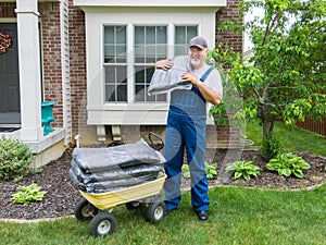 Man unloading bags of mulch from a wheelbarrow