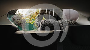 A man unloads winter tires from a car trunk