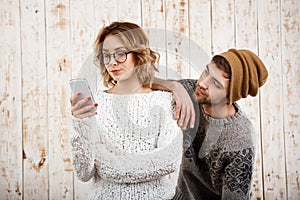 Man unnerve his girlfriend looking at phone over wooden background.