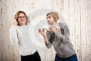 Man unnerve his girlfriend speaking on phone over wooden background.