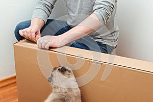 Man unpacking box with new furniture at home. Moving house day and real estate concept. Funny cat at home