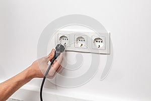 Man unplugging cord from a electrical outlet