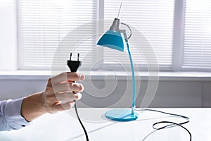 Man Unplugging Lamp To Save Electricity photo