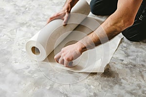 Man unraveling a rolled white wallpaper, illustrating home renovation and interior design in process