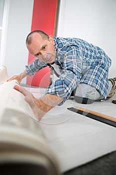 Man unrolling carpert on floor house