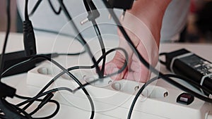 A man unsafely removes live electrical wires and plugs from an electrical surge protector. Cotsnept safety violation