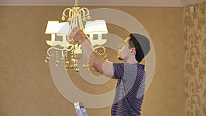 A man unscrews a burnt out light bulb