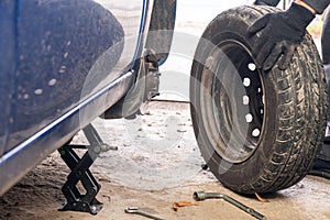 A man unscrews a car wheel in a garage. Replacing car wheels