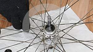A man unscrews the cone of a ball bearing. Disassembles the rear wheel hub of a mountain bike. The bushing bearing balls are