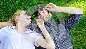 Man unshaven and girl lay on grass meadow. Couple in love united with nature. Nature fills them with freshness and