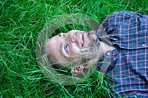 Man unshaven guy lay on green grass meadow. Guy happy and peaceful enjoy freshness of grass. Closer to nature. Man