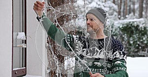 man untangle christmas lights outdoors for house exterior decoration