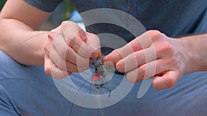 Man untangles a fishing line and hooks preparing to fishing, hands closeup.