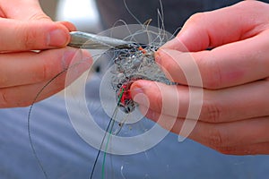 Man untangles a fishing line and hooks preparing to fishing, hands closeup.